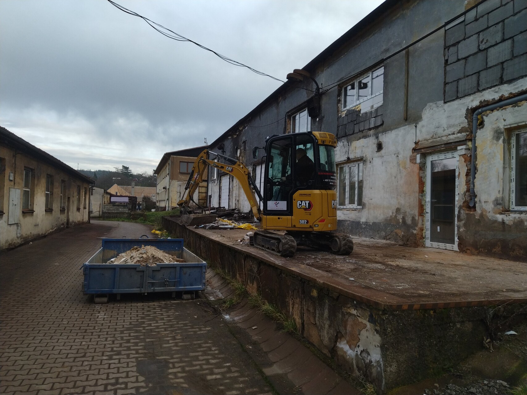 Minibagr CAT 302 při práci u budovy